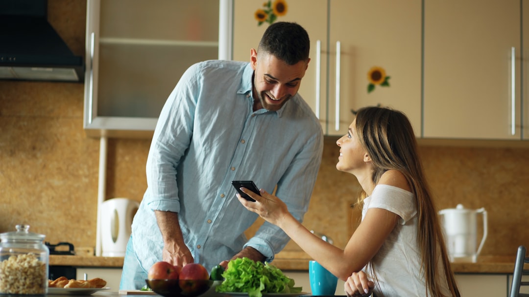 Couple checking their mortgage deal on a phone in their kitchen - product transfer vs remortgage